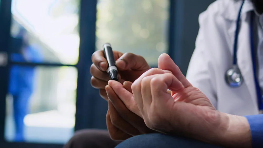 A patient undergoing blood glucose levels check up by the doctor